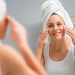 woman is facing the mirror while putting moisturizer on her face