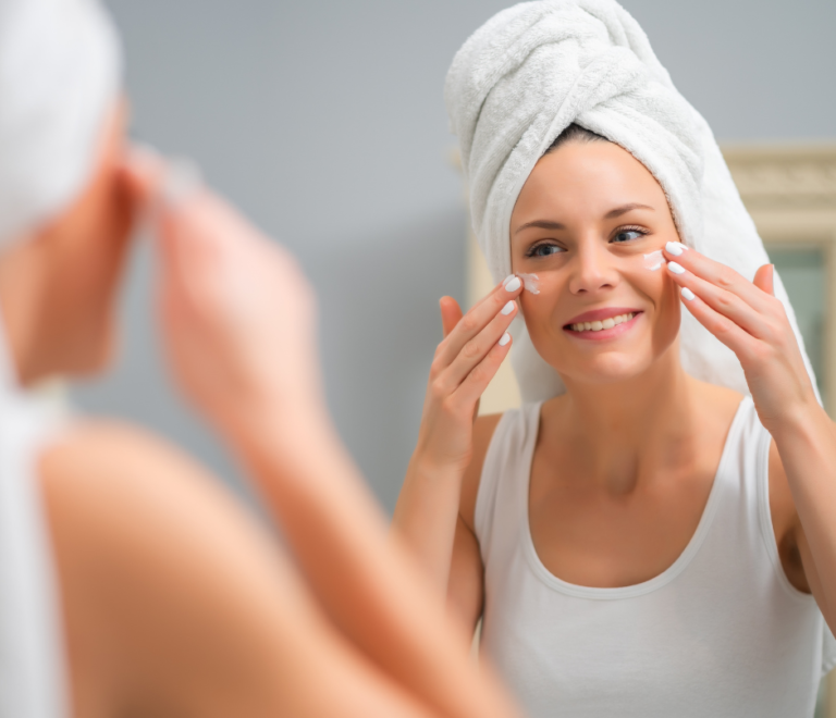 woman is facing the mirror while putting moisturizer on her face