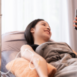 smiling woman holding phone while having iv therapy