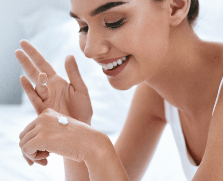 beautiful woman putting lotion on hands