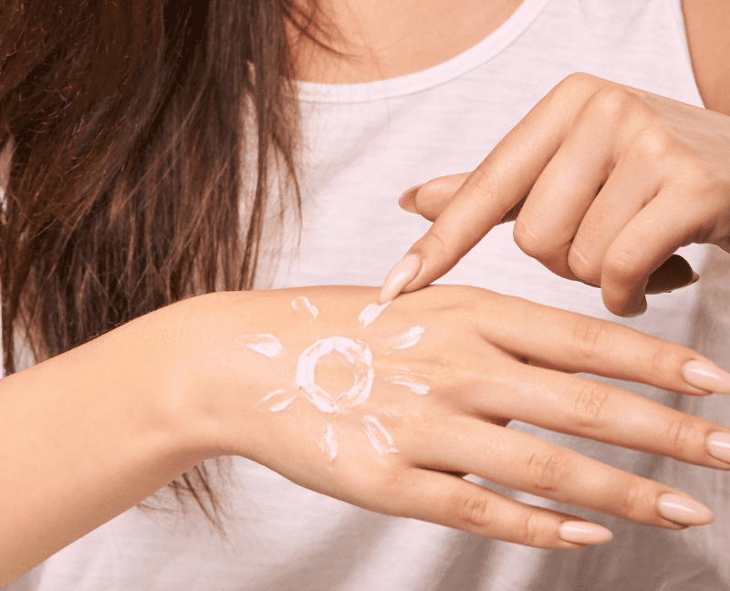 woman applying sunscreen shape of sun on hands for healthy winter skin