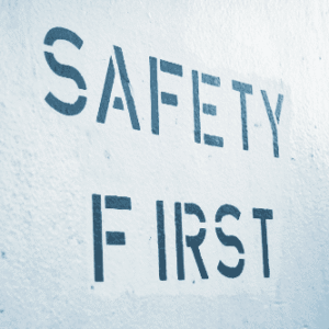 Stenciled "SAFETY FIRST" sign painted in dark blue on a textured wall.
