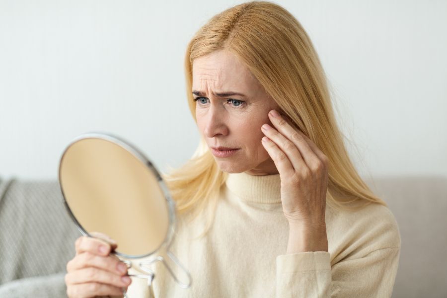 woman looking at mirror worried about glabellar lines