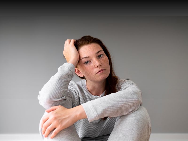 woman in grey outfit looking sad