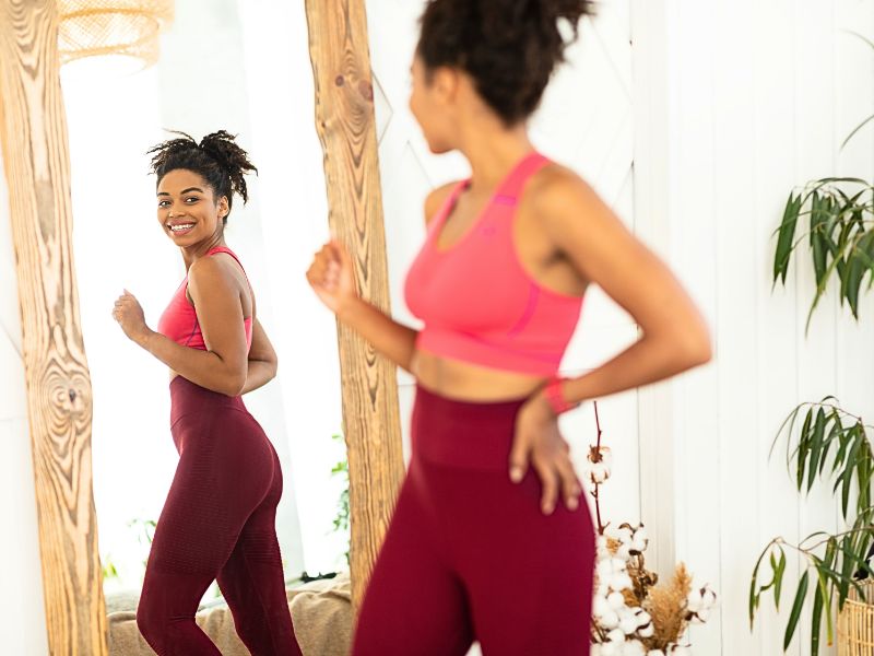 woman looking at her body for weight loss in the mirror