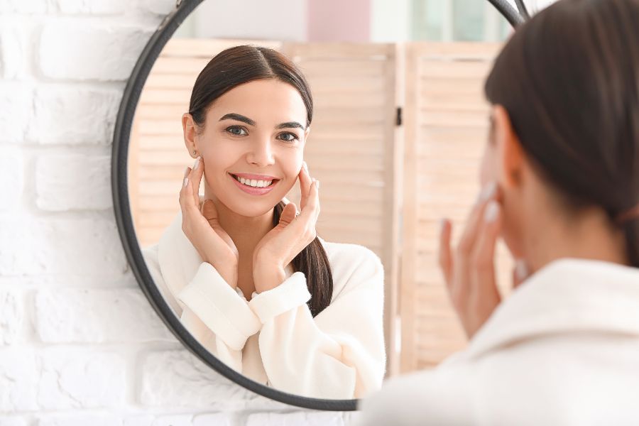 woman looking at her skin in the mirror