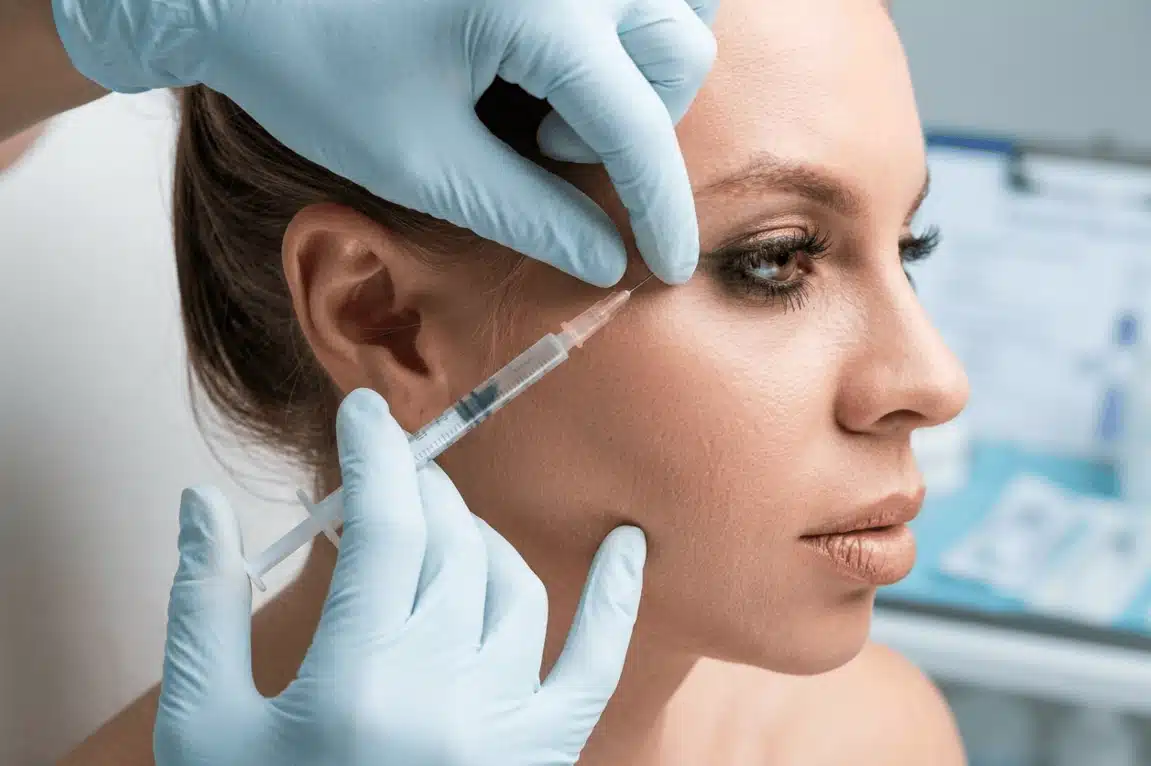 Side profile of a woman receiving a targeted Botox injection in the temple area.