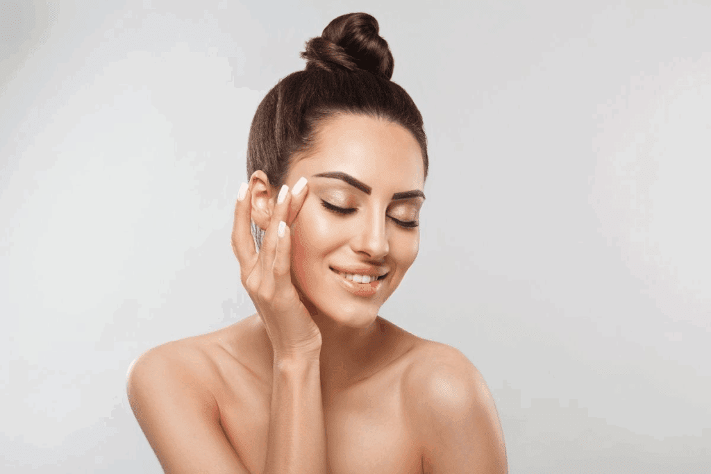 A woman calmly touches her cheek, illustrating skincare concerns and the importance of acne facials for persistent breakouts.
