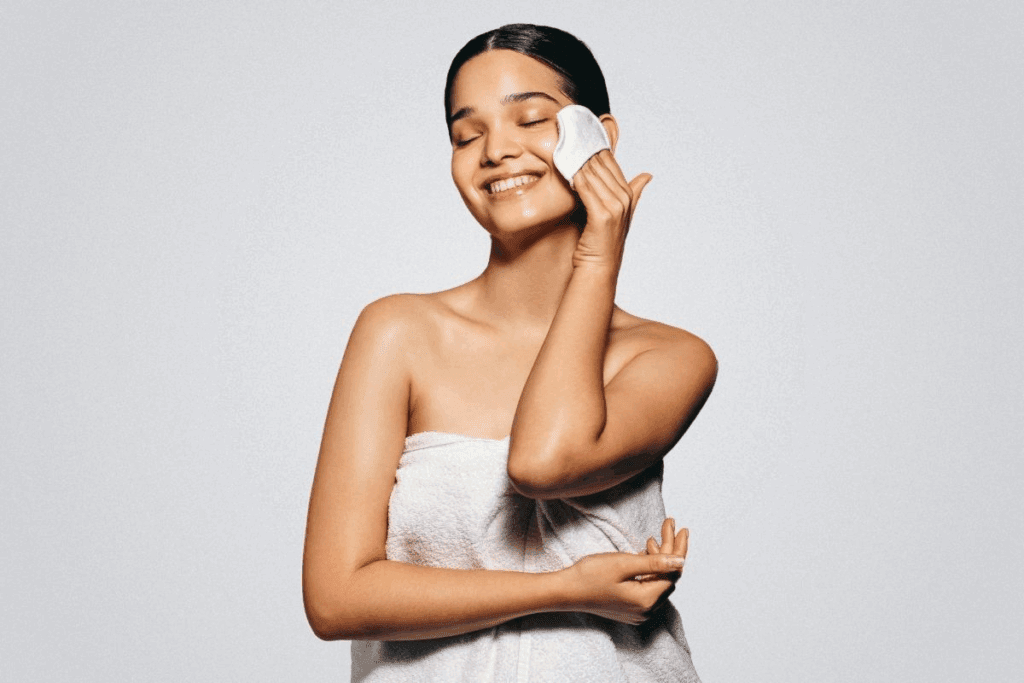 Close-up of a woman cleansing her face with a cotton pad during an acne facial, a gentle step to help treat stubborn breakouts
