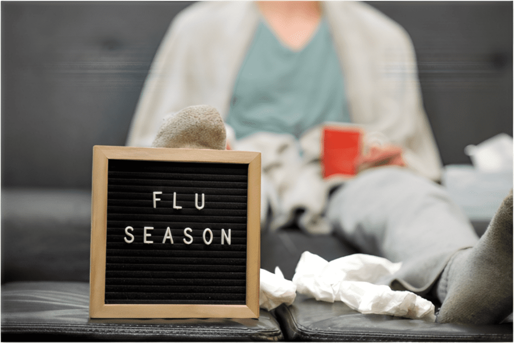 Person resting during flu season with a sign, highlighting the need for IV therapy immune support and wellness.