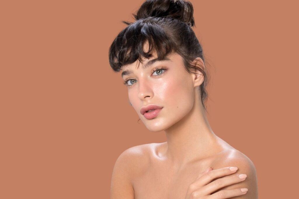 Woman with hair in a bun smiles softly, representing natural beauty and wellness benefits when clients get IV therapy for hydration support.