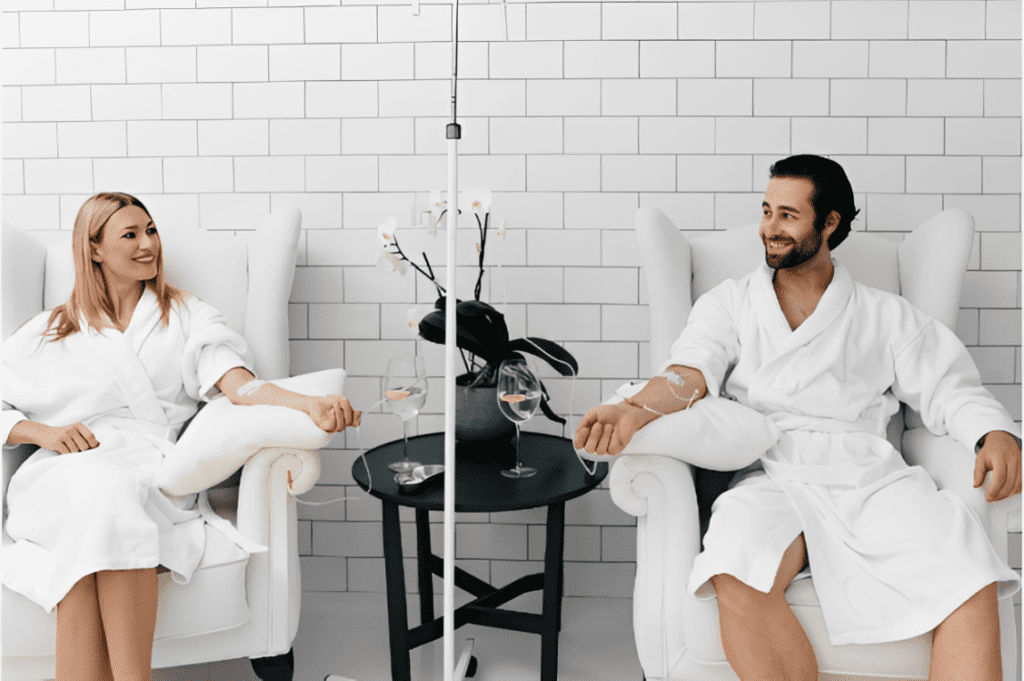 Couple in white robes receiving IV therapy immune support to boost their defenses at a luxury wellness clinic.