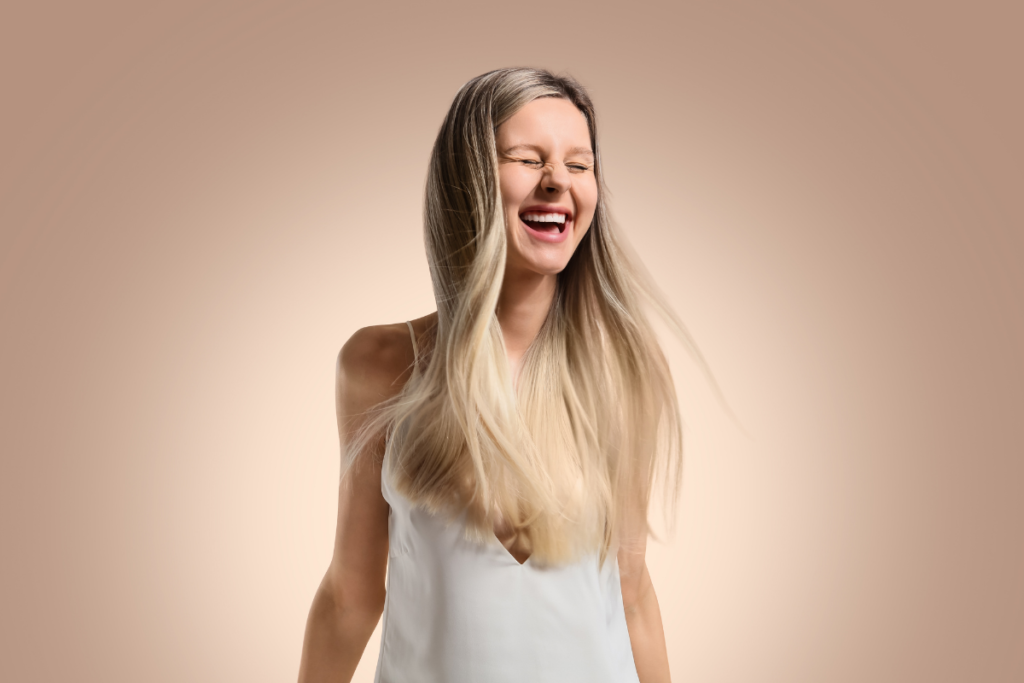 Joyful blonde woman laughing with flowing hair.