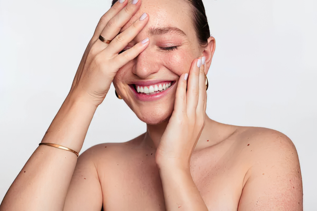 Woman smiling with hands resting on her face.