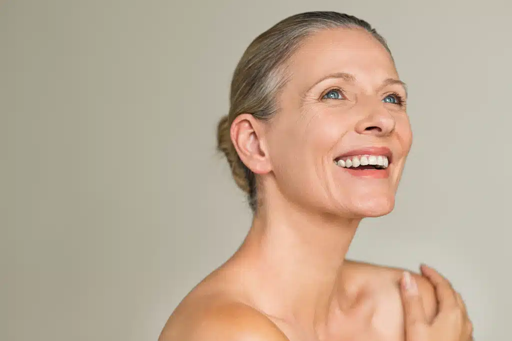 Smiling mature woman with pulled-back grey hair showcasing smooth, radiant facial skin.