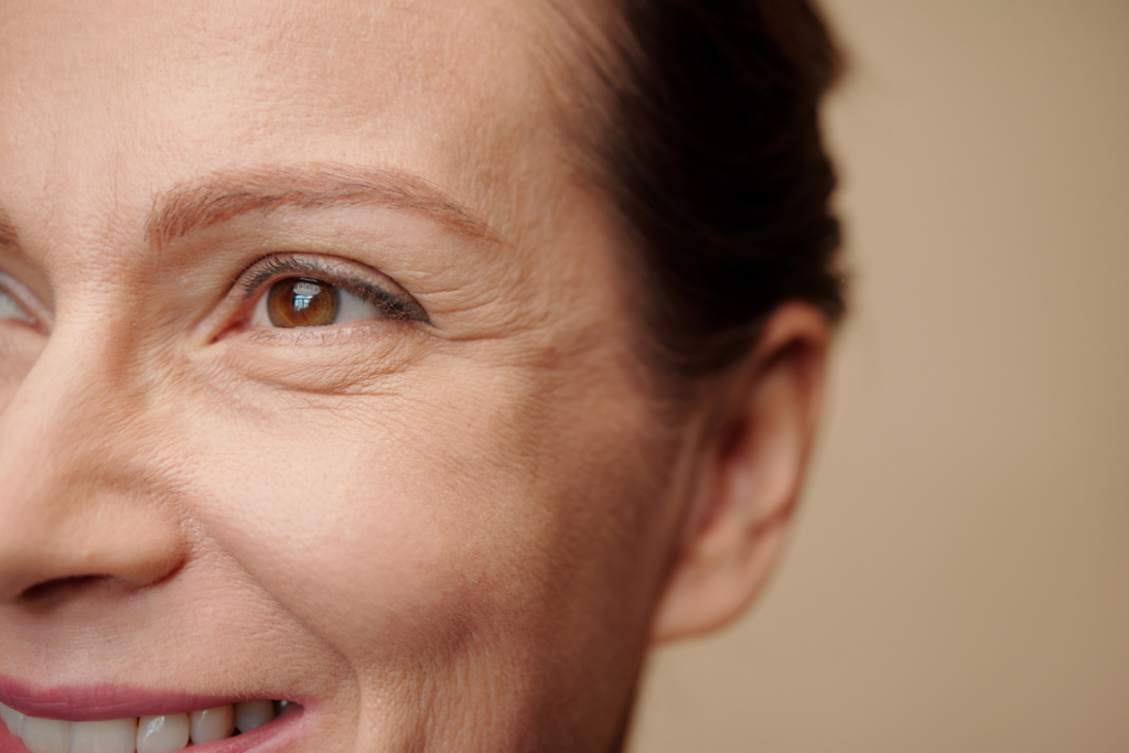 Close-up of a smiling mature woman showing fine lines and crow's feet around her eyes.