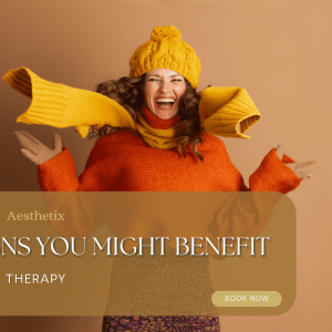 A joyful woman in a bright orange sweater, yellow scarf, and hat gleefully poses against a warm beige background, highlighting IV therapy benefits.