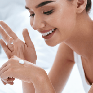 beautiful woman putting lotion on hands